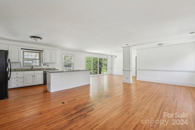 kitchen featuring white cabinets, black fridge, sink, light hardwood / wood-style flooring, and a notable chandelier