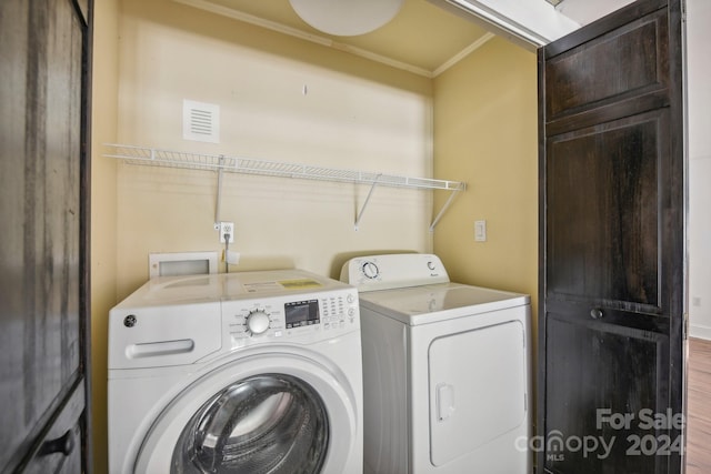 laundry room with wood-type flooring, crown molding, and washer and clothes dryer