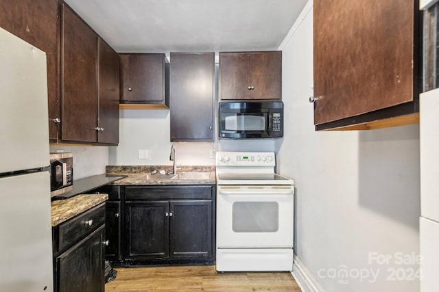 kitchen featuring white appliances, dark brown cabinetry, sink, and light wood-type flooring