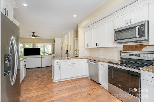 kitchen featuring stainless steel appliances, sink, ceiling fan, white cabinets, and light hardwood / wood-style floors