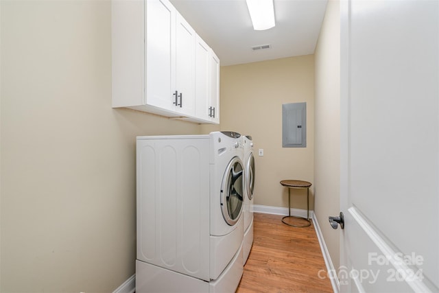 washroom with electric panel, cabinets, washing machine and clothes dryer, and light hardwood / wood-style floors