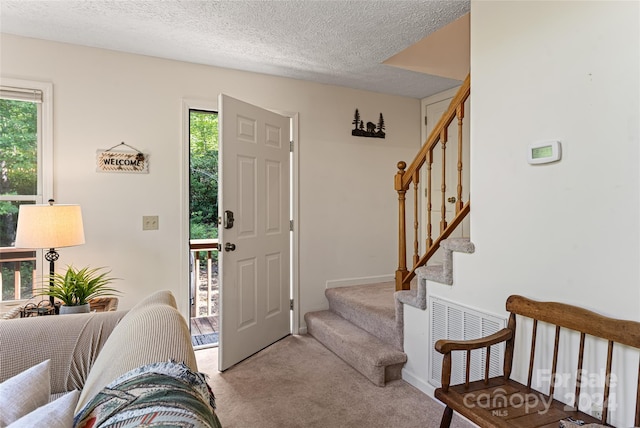 foyer featuring carpet and a textured ceiling