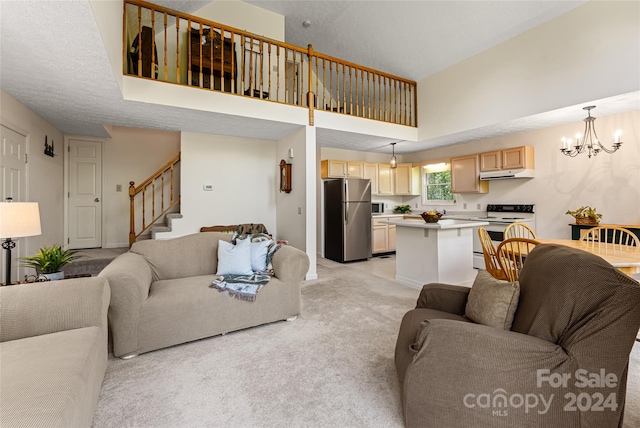 living room featuring a towering ceiling, an inviting chandelier, and light colored carpet