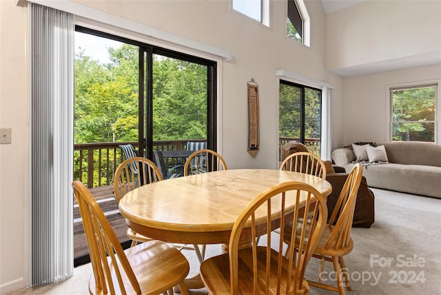 dining room with a towering ceiling and light carpet