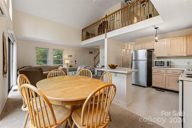 carpeted dining area featuring a high ceiling