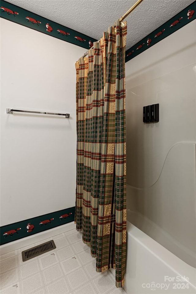 bathroom with tile patterned flooring, a textured ceiling, and shower / tub combo with curtain