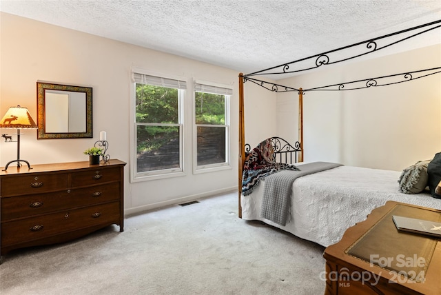 bedroom featuring a textured ceiling and light carpet