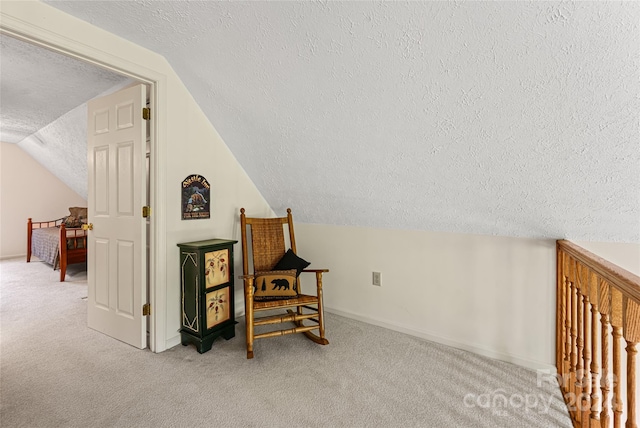 sitting room with a textured ceiling, vaulted ceiling, and light colored carpet