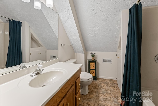 full bathroom with vaulted ceiling, vanity, tile patterned flooring, a textured ceiling, and toilet