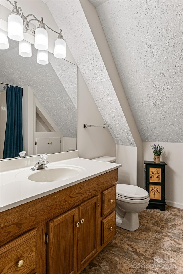 bathroom featuring a textured ceiling, vanity, lofted ceiling, and toilet