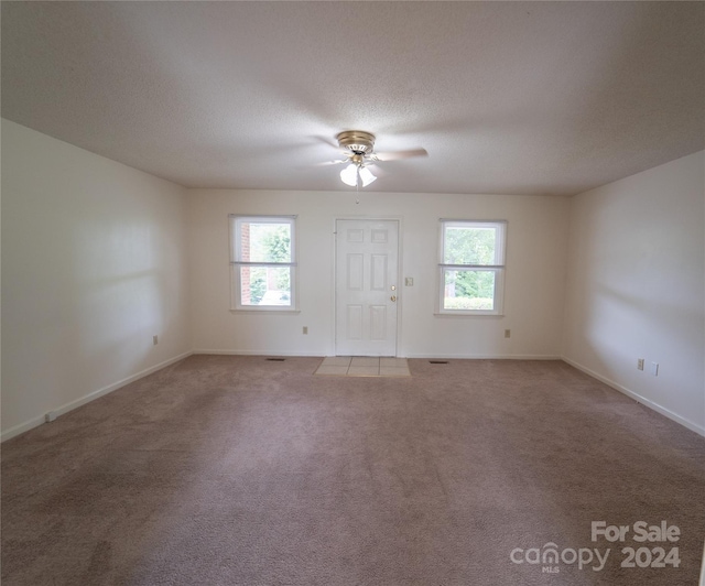 carpeted empty room with a textured ceiling, ceiling fan, and baseboards