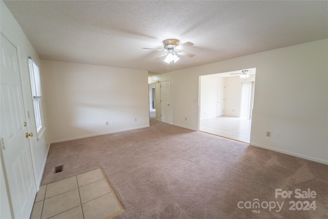 spare room featuring a textured ceiling, visible vents, and light colored carpet