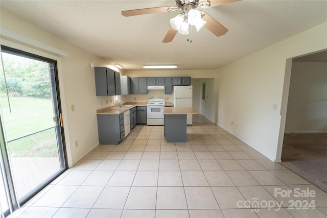 kitchen featuring white appliances, light tile patterned floors, light countertops, gray cabinetry, and under cabinet range hood