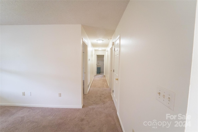 corridor featuring light carpet and baseboards