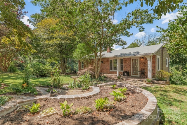 view of front of home with brick siding, a chimney, and a front lawn