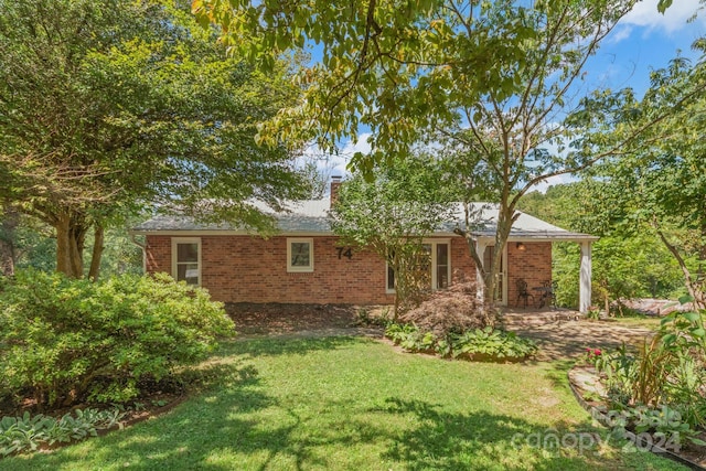 view of front of house with a chimney, a front lawn, and brick siding