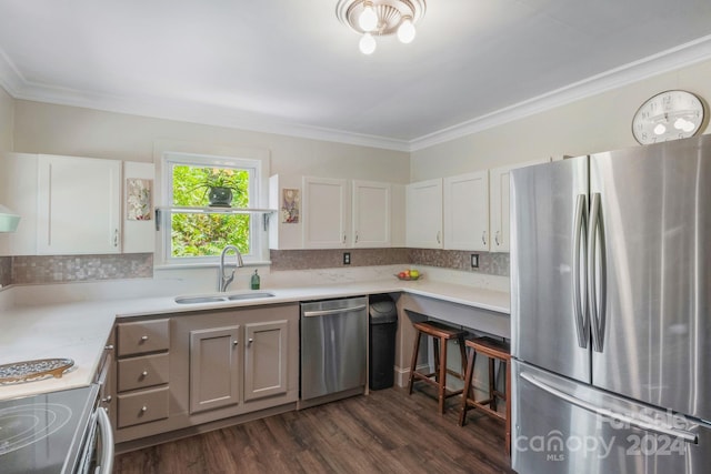 kitchen with ornamental molding, light countertops, appliances with stainless steel finishes, and a sink