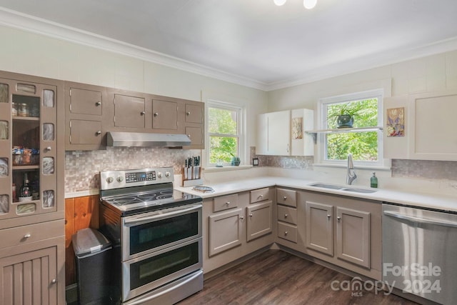 kitchen featuring under cabinet range hood, a sink, light countertops, ornamental molding, and appliances with stainless steel finishes