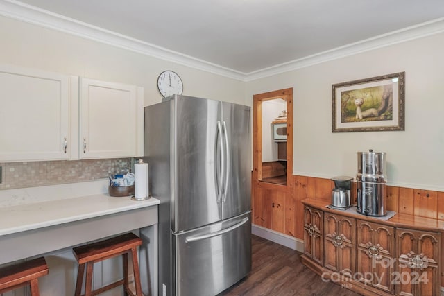 kitchen with a breakfast bar area, light countertops, ornamental molding, freestanding refrigerator, and dark wood-style floors