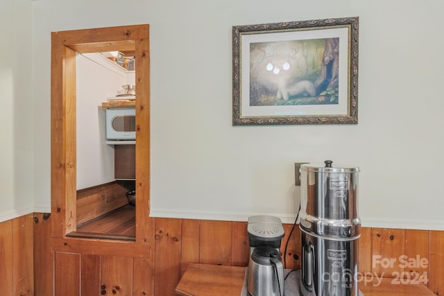 interior details with a wainscoted wall, white microwave, and wooden walls