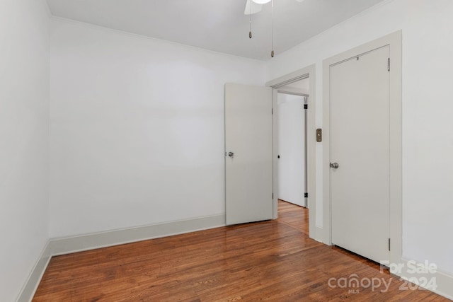 empty room with crown molding, baseboards, and wood finished floors