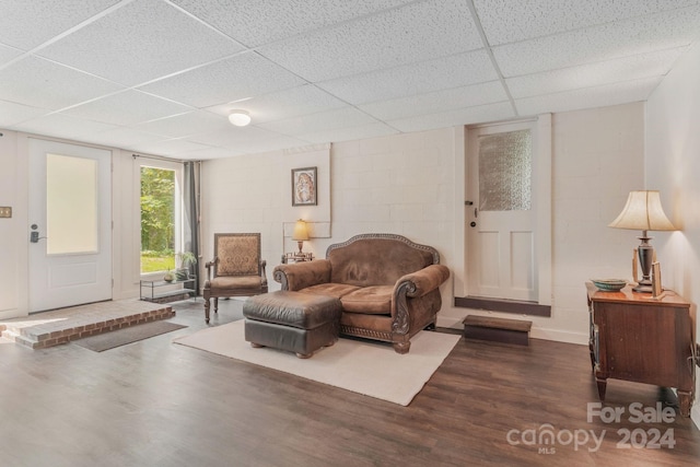 living room with concrete block wall, a paneled ceiling, and wood finished floors