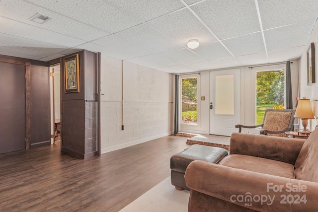 living room featuring concrete block wall, visible vents, plenty of natural light, and wood finished floors