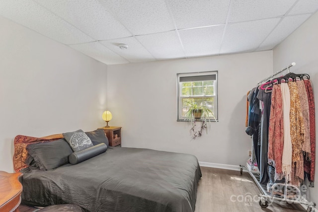 bedroom featuring a paneled ceiling, baseboards, and wood finished floors