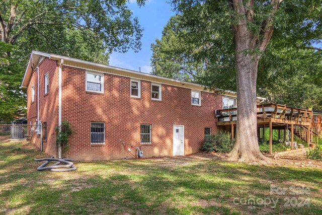 rear view of house with a wooden deck and a yard