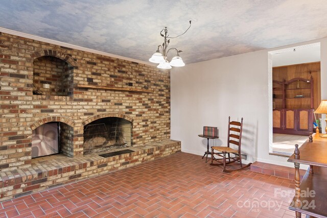 living room featuring a textured ceiling, crown molding, a chandelier, and a fireplace