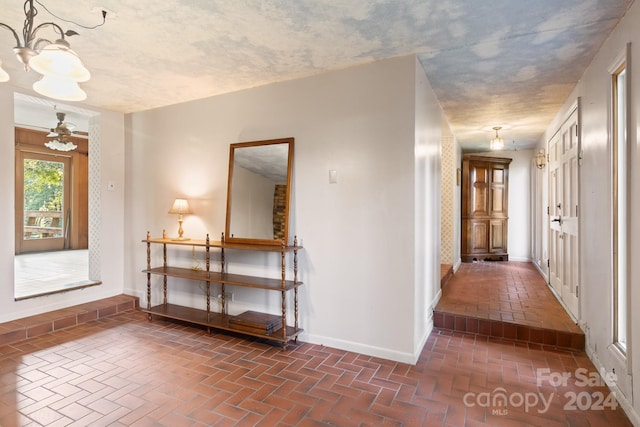 1573 Timberlake Dr, Shelby, NC 28150 - hallway featuring a chandelier, a textured ceiling, brick floor, and baseboards