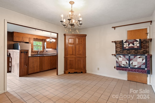 1573 Timberlake Dr, Shelby, NC 28150 - kitchen with light tile patterned floors, decorative backsplash, dark countertops, a notable chandelier, and brown cabinets