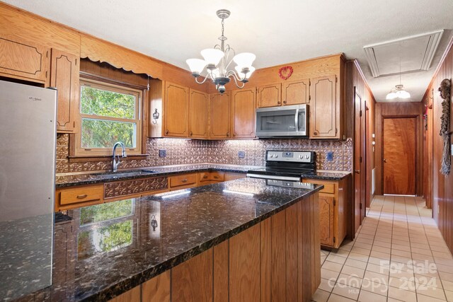 kitchen featuring dark stone counters, backsplash, stainless steel appliances, and hanging light fixtures