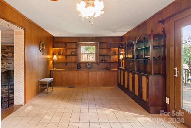 tiled living room with crown molding, wood walls, and a chandelier