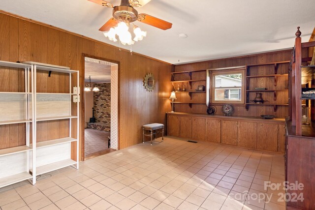 kitchen featuring tile patterned floors, ceiling fan, ornamental molding, and wooden walls