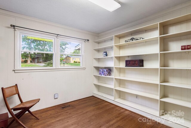 unfurnished room featuring crown molding, dark wood-type flooring, wood walls, and a textured ceiling