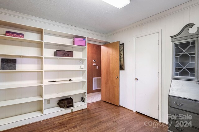 unfurnished bedroom featuring a textured ceiling, ornamental molding, and hardwood / wood-style flooring