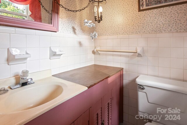 bathroom featuring tile walls, toilet, vanity, and tasteful backsplash