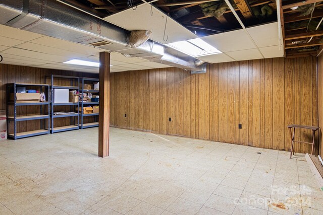 basement with a paneled ceiling and wooden walls