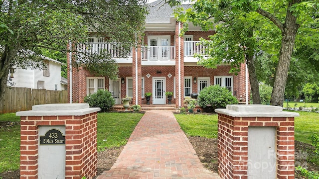 view of front of home featuring a balcony, fence, and brick siding