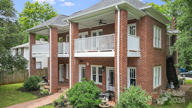 view of front facade featuring brick siding, fence, a balcony, and roof with shingles