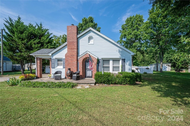 bungalow-style home with a front yard, brick siding, a patio, and a chimney