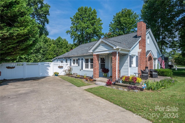 view of front of home with brick siding, a shingled roof, fence, a gate, and a chimney