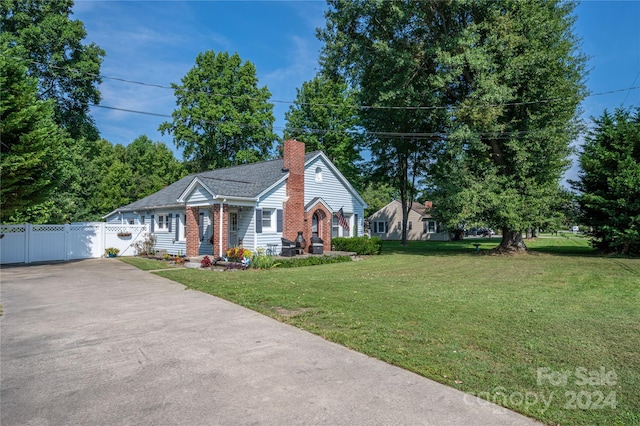 view of front of property featuring brick siding, a chimney, a gate, fence, and a front yard