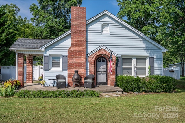 view of front of property with brick siding, a shingled roof, a chimney, fence, and a front yard