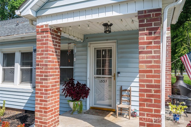 property entrance featuring covered porch and brick siding