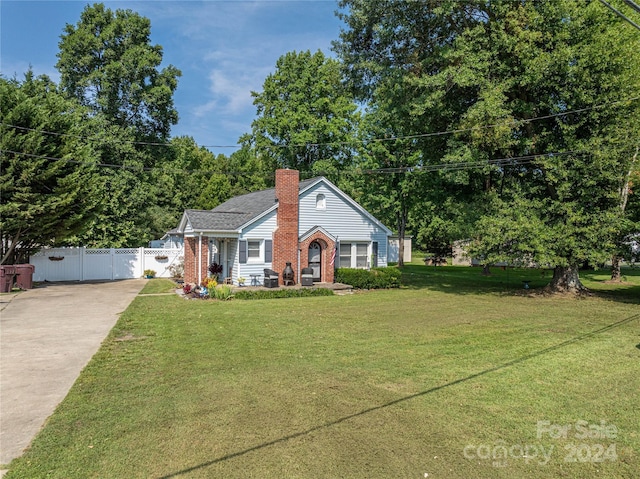 view of front facade featuring brick siding, fence, a gate, a chimney, and a front yard