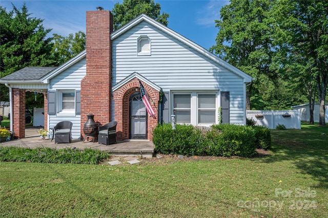 view of front facade with a front yard, brick siding, and a chimney