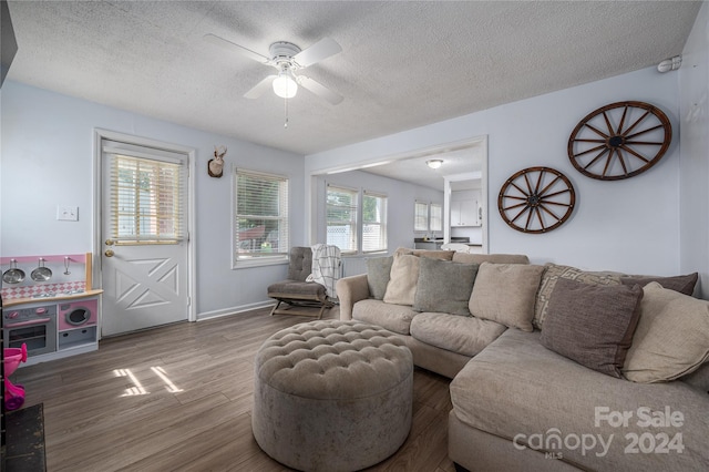 living area featuring a ceiling fan, a textured ceiling, baseboards, and wood finished floors