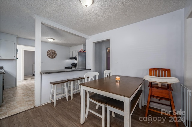 dining space with a textured ceiling and wood finished floors